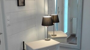 A white vanity with a mirror, a black lamp, and a small framed sign on the wall.