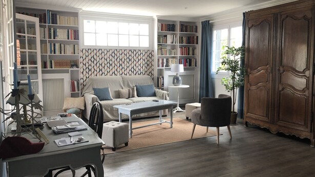 A living room with a sofa, coffee table, and bookshelves filled with books.