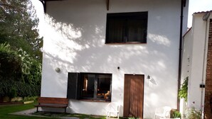 A white building with a wooden bench, two white chairs, and a potted plant. - Chalet House Honorato San Rafael routes of (San Rafael)