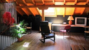 A room with a wooden ceiling, a desk with a computer, a chair, a TV, and a potted plant. - Chalet House Honorato San Rafael routes of (San Rafael)
