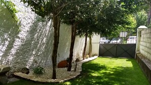 A well-maintained garden with a stone wall, a grassy lawn, and a tree-lined path. - Chalet House Honorato San Rafael routes of (San Rafael)