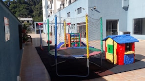 Un parque infantil con un trampolín y una casita de juegos.
