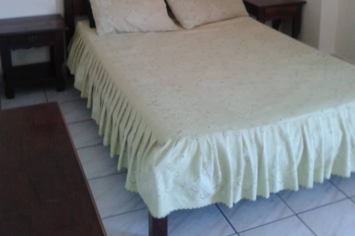 Ein Schlafzimmer mit einem Bett, zwei Nachttischen, einem Beistelltisch und einem Holzboden über dem Bett.
