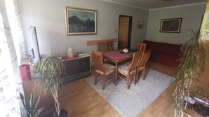Ein Essbereich mit einem Holztisch und Stühlen, einem Bild an der Wand und topfgepflanzten Pflanzen.