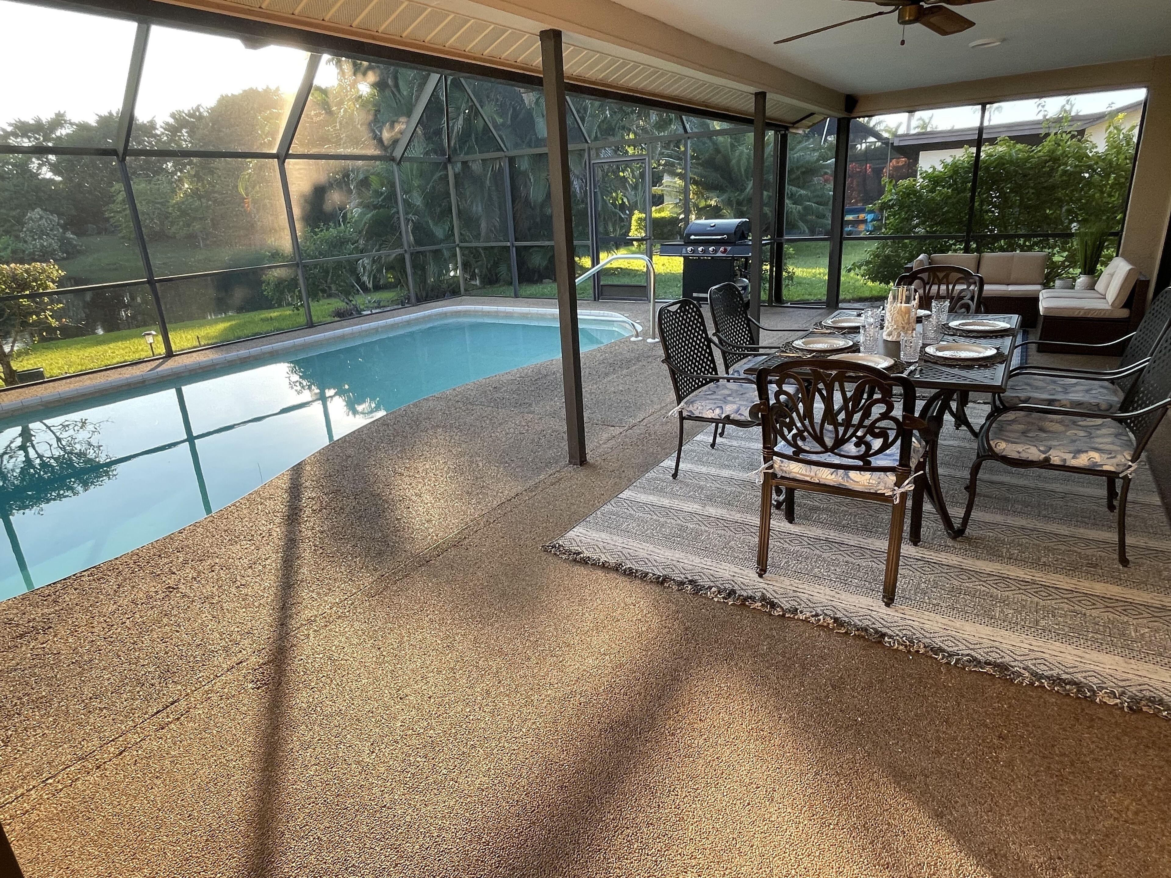 Un espacio al aire libre cubierto con piscina, mobiliario de patio y una parrilla.