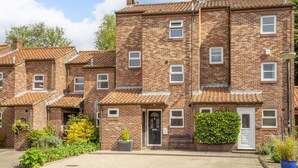 A row of brick townhouses with a tiled roof, a front garden, and a visible front door. - 12 Pear Tree House - sleeps 4 guests  in 2 bedrooms (York)