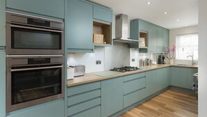 A modern kitchen with two built-in ovens, a gas stove, and teal cabinetry. - 12 Pear Tree House - sleeps 4 guests  in 2 bedrooms (York)