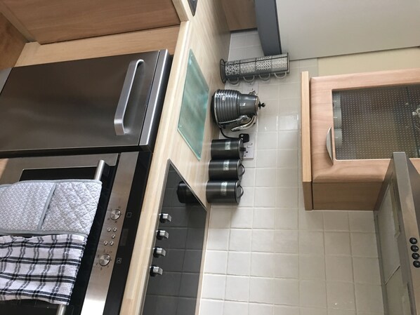 Eine Küche mit Edelstahlbackofen, Wasserkocher und Kaffeemaschine auf der Arbeitsfläche.