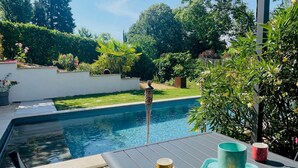 A poolside area with a table, a drink tray, and a pool with a water feature. - Studio Anemone: self-catering cottage in Sarlat with private heated pool (Sarlat-la-Canéda)