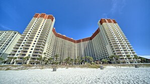 Un hotel di grandi dimensioni con una facciata curva, numerosi balconi e vista sulla spiaggia.