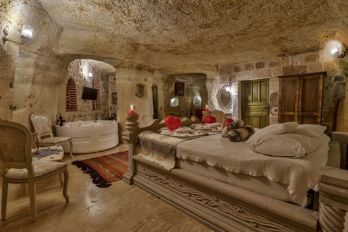 Ein Schlafzimmer mit einem großen Bett, einer Sitzecke mit einem Sessel, einer Badewanne und einem Spiegel.