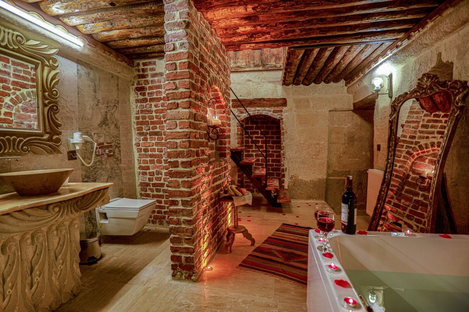 A rustic bathroom with a brick wall, a wooden staircase, and a bathtub.