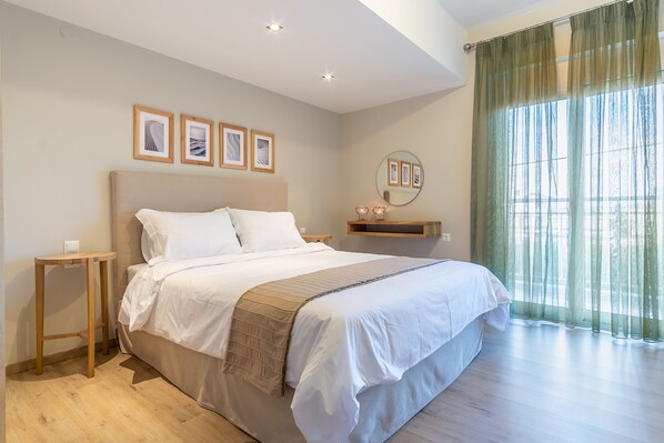 A bedroom with a large bed, a bedside table, a mirror, and framed pictures on the wall.