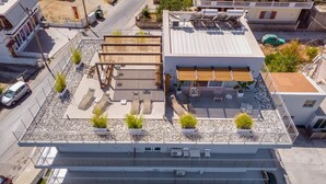 Vista aérea de una terraza en la azotea con mobiliario exterior, una pérgola y plantas en macetas.