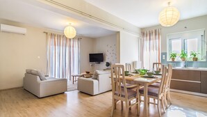 Una sala moderna con un sofá, una mesa de comedor, sillas y un televisor.