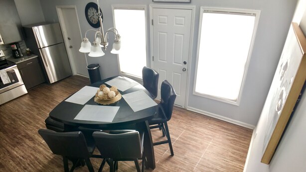 A kitchen with a dining table, chairs, a clock, and a refrigerator. - Spacious Townhouse. 3B & 1. 5 baths. 10 Min to Airport. Free parking. (North Charleston)