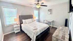 A bedroom with a bed, nightstands, a desk, a chair, a ceiling fan, and a TV. - Spacious Townhouse. 3B & 1. 5 baths. 10 Min to Airport. Free parking. (North Charleston)