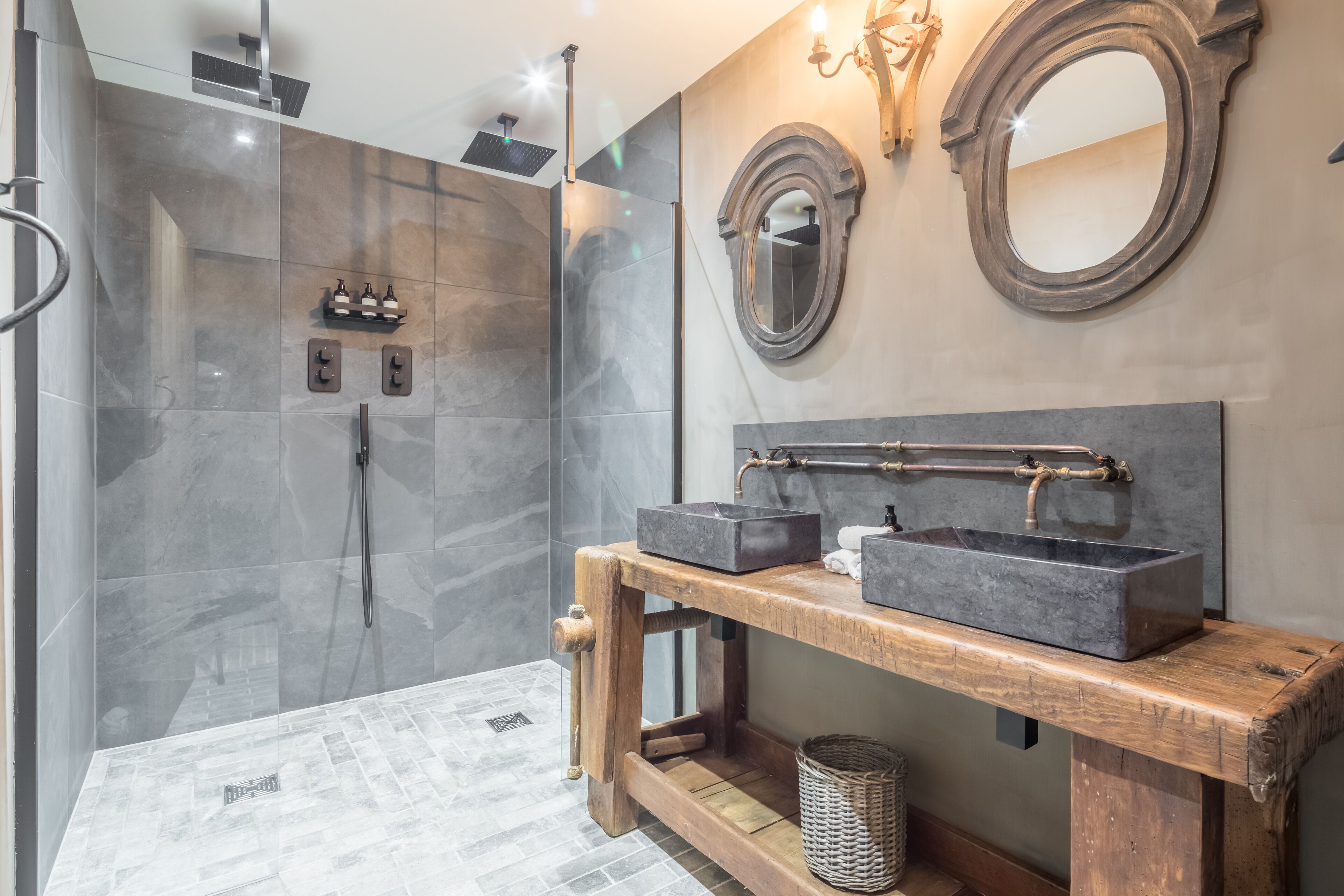 A modern bathroom with a glass-enclosed shower, a wooden vanity with a basin, and two wall-mounted mirrors.