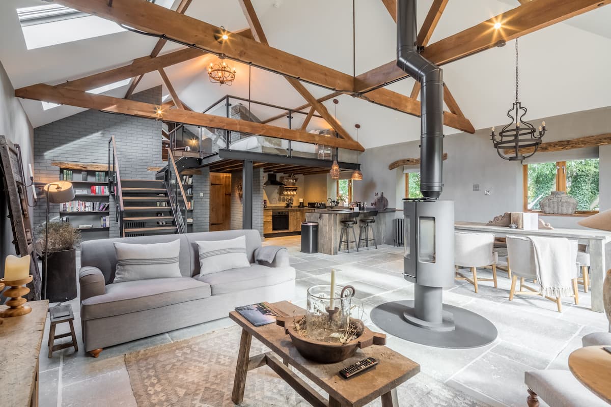A spacious living area with a high ceiling, exposed wooden beams, a fireplace, and a cozy seating arrangement.