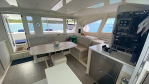A compact galley with a central table, seating area, and a control panel. - Luxury Catamaran Sailing Trips in the Exumas & Staniel Cay area (Staniel Cay)