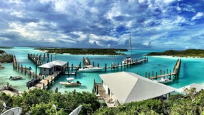A marina with docked boats, a small house, and a beach. - Luxury Catamaran Sailing Trips in the Exumas & Staniel Cay area (Staniel Cay)
