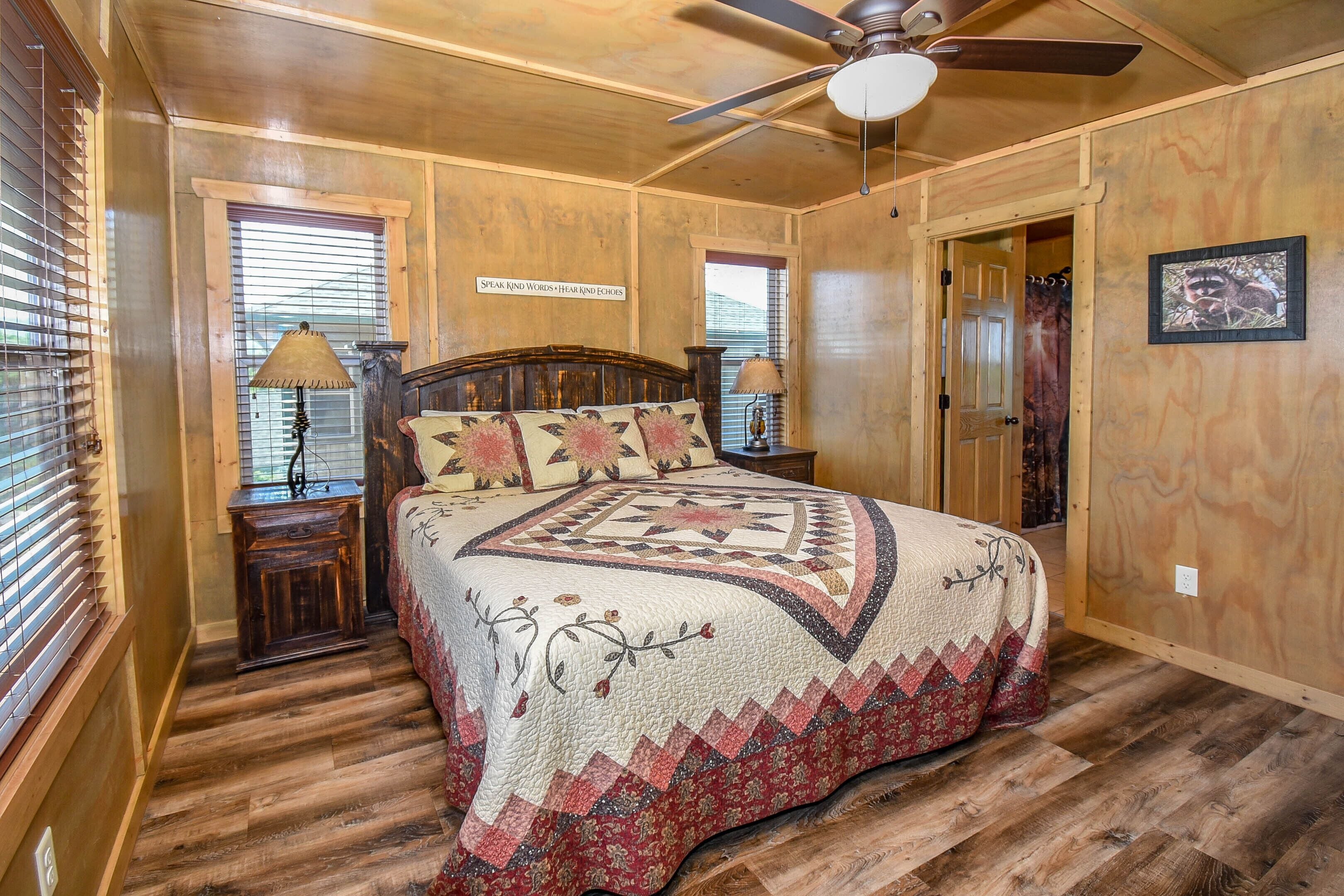 Ein Schlafzimmer mit Holzboden, einem Bett mit Steppdecke, einem Deckenventilator und einem Schild an der Wand.