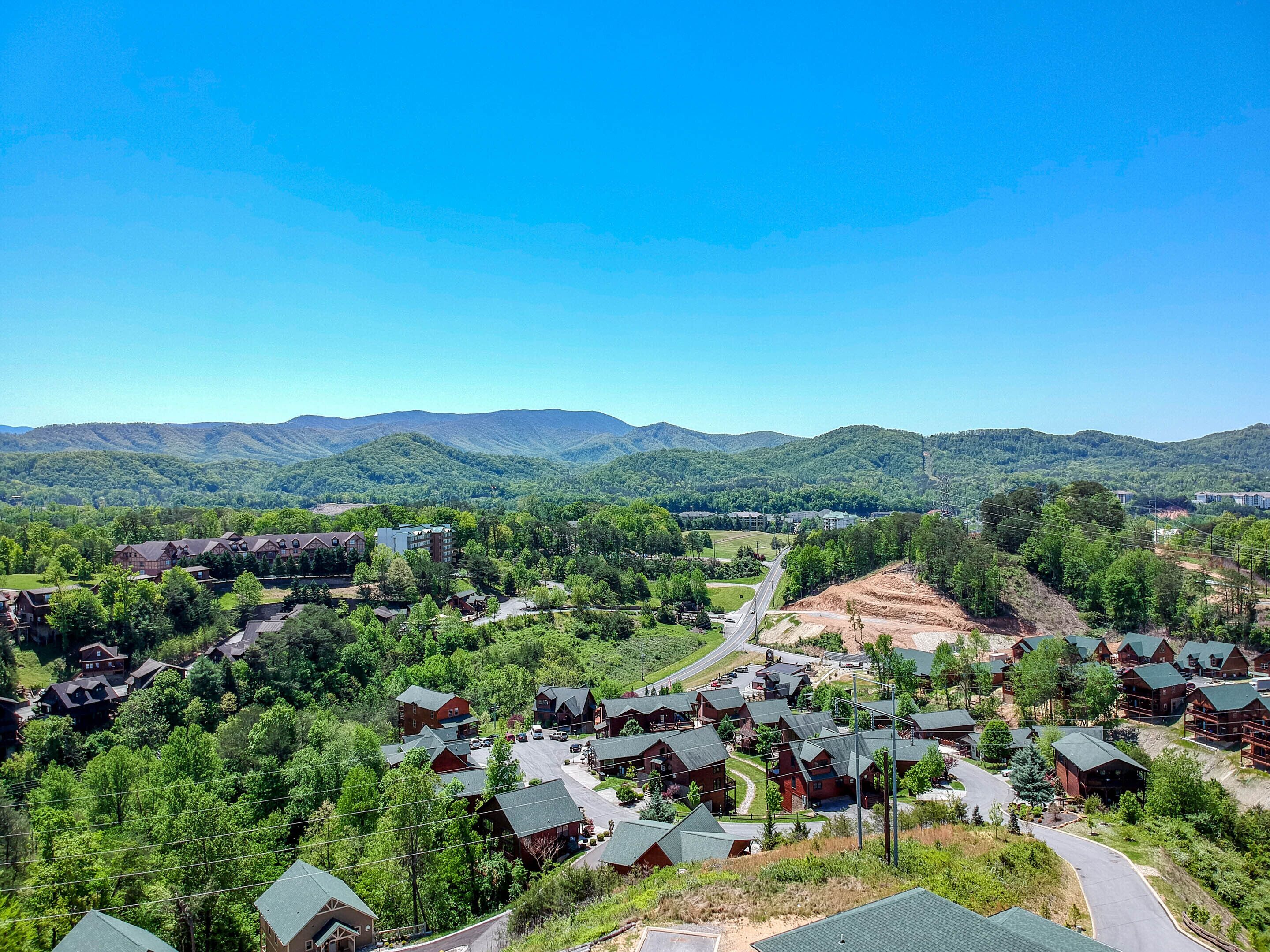 A mountain resort with log cabins, a main lodge, and a road leading to the main building.