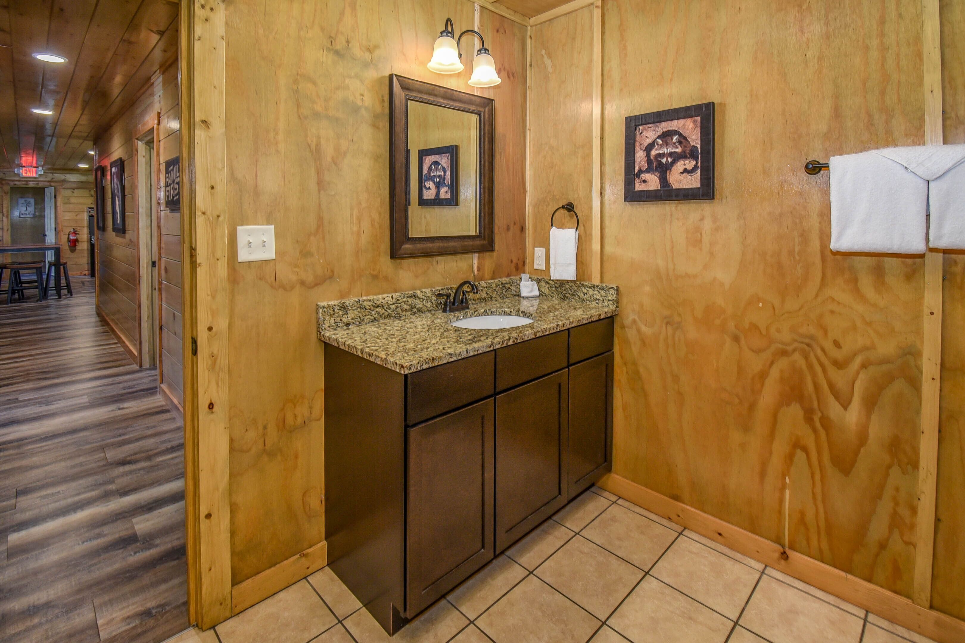 Une salle de bain en bois avec un lavabo en granit, des meubles en bois et des tableaux encadrés accrochés au mur.
