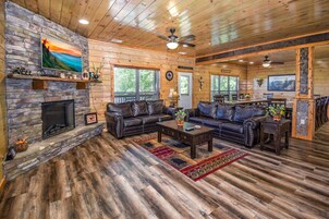 A spacious living room with a stone fireplace, leather sofas, and a dining area with a view of the outdoors.