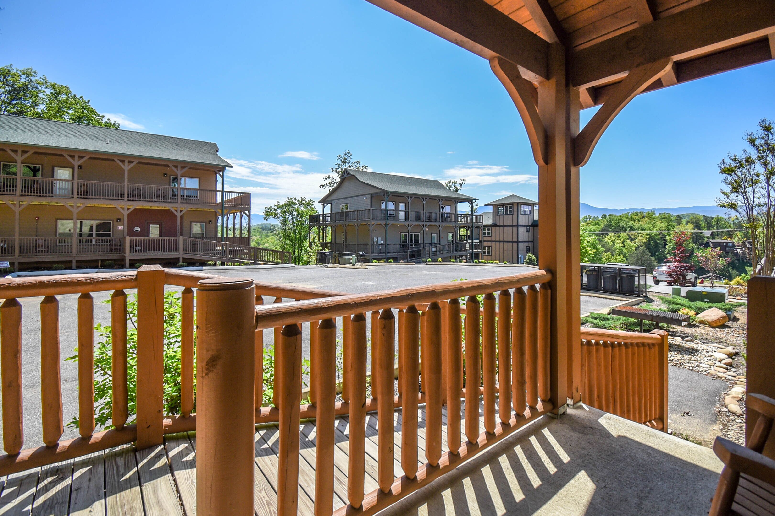 A wooden deck with a view of a multi-story building with balconies and a covered area.