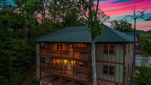 A two-story cabin with a balcony, surrounded by trees and a lake. - SmokyStays 10 Bedroom Cabin (Pigeon Forge)
