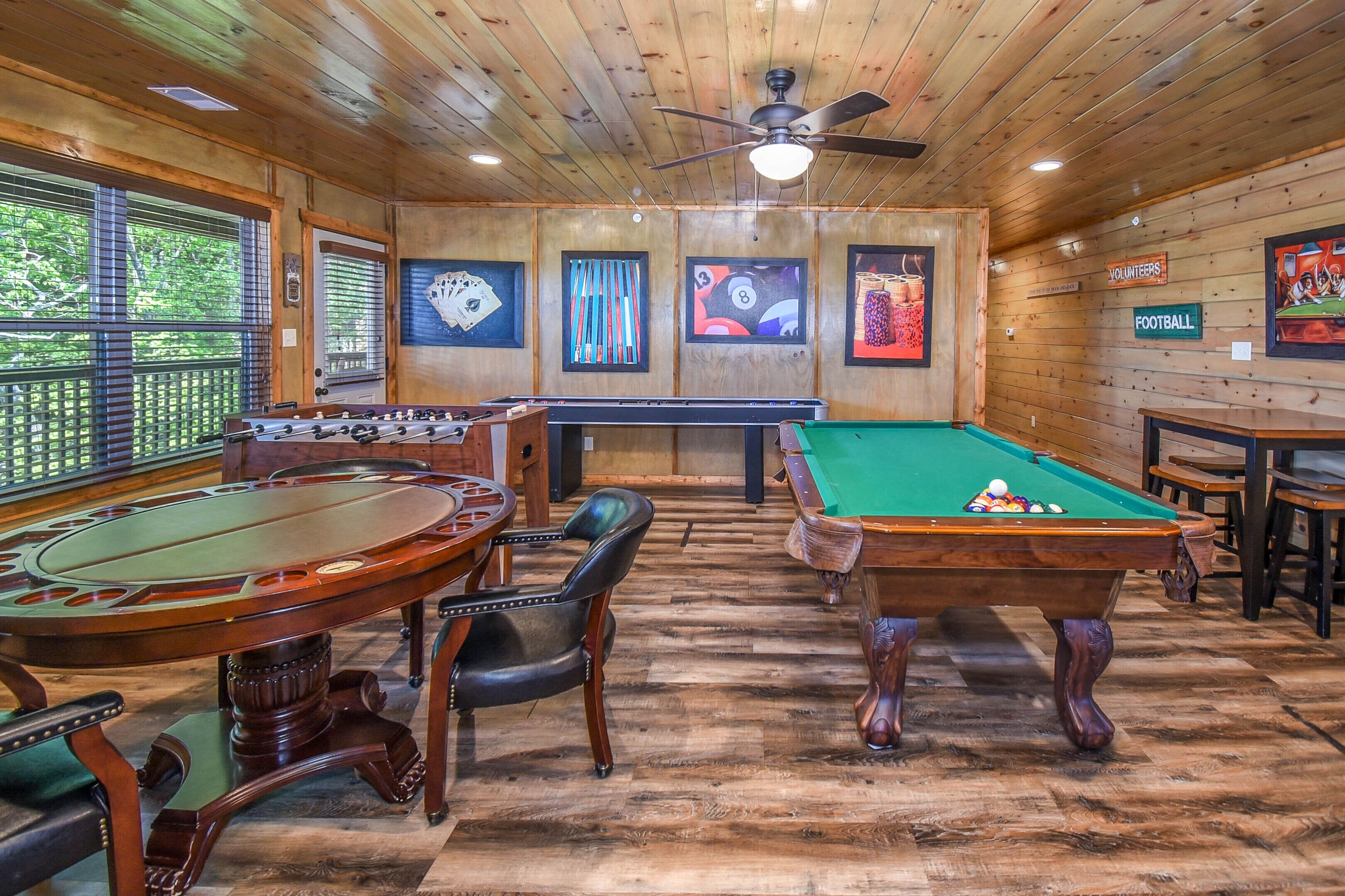 A pool table with a green felt surface, a foosball table, and a billiards table with a striped cloth.