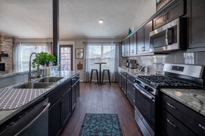 A modern kitchen with dark cabinetry, stainless steel appliances, and a central island.