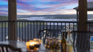 Un espace repas offrant une vue sur un lac et des collines, avec une table décorée de bougies et de bouteilles.