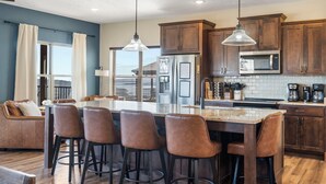 A modern kitchen with wooden cabinets, stainless steel appliances, and a central island with bar stools. - Lake View Escape - Sleeps 22, Game Room, Indoor Pool (Branson)