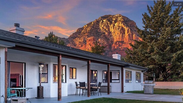 Ein Haus mit überdachter Terrasse, Kamin und Bergblick.