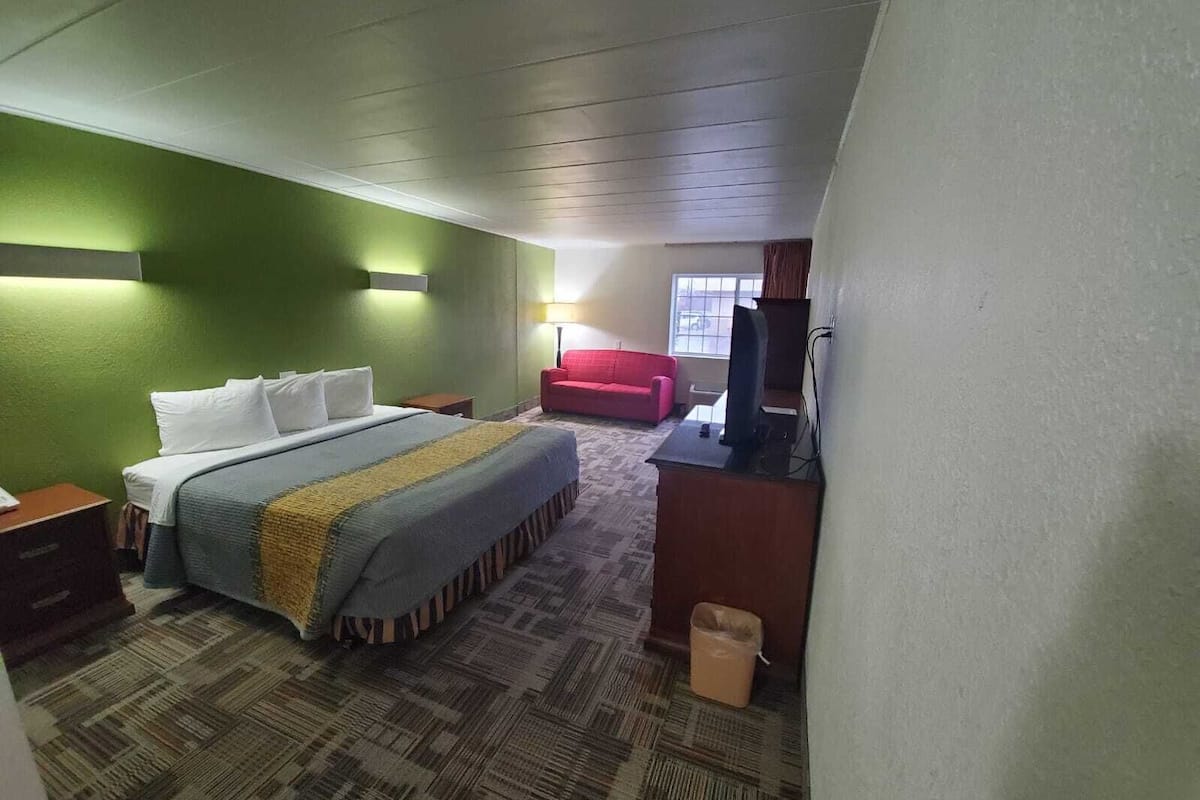 A hotel room with a bed, a desk, a chair, and a window.