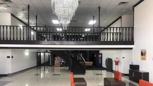 A spacious lobby with a staircase, seating area, and a Pepsi vending machine. - Shadeland Inn Indianapolis (Indianapolis)