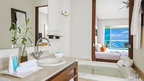 Une salle de bain moderne avec une baignoire, deux lavabos, un meuble-lavabo et un grand miroir.