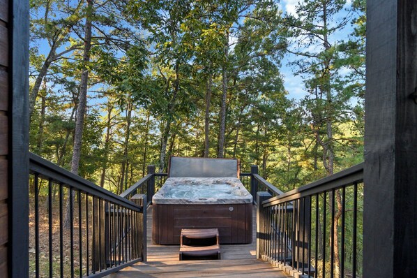 A hot tub on a wooden deck surrounded by trees.