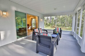 A covered patio area with wicker furniture and a glass door leading to an interior space. - SASSA Boutique Homes (Homosassa)