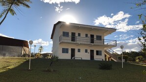 Un edificio de dos pisos con balcón, escalera y un césped bien cuidado.