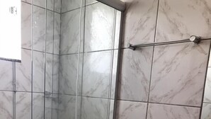 Un baño con ducha de vidrio, inodoro y lavamanos.
