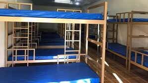 Un dormitorio con literas, estructuras de madera y ropa de cama azul.