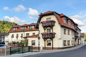 Um edifício tradicional em estilo europeu, com várias varandas, fachada de tijolos e telhado de telhas vermelhas.