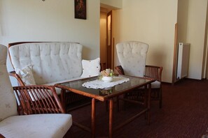 Ein Zimmer mit einem Glastisch, zwei Polsterstühlen und einer Couch.