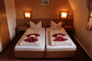 Ein Doppelzimmer mit zwei Betten, jeweils einem Nachttisch, Nachttischlampen und einem gerahmten Bild an der Wand.
