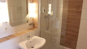 A bathroom with a white sink, a mirror, and a glass-enclosed shower area.