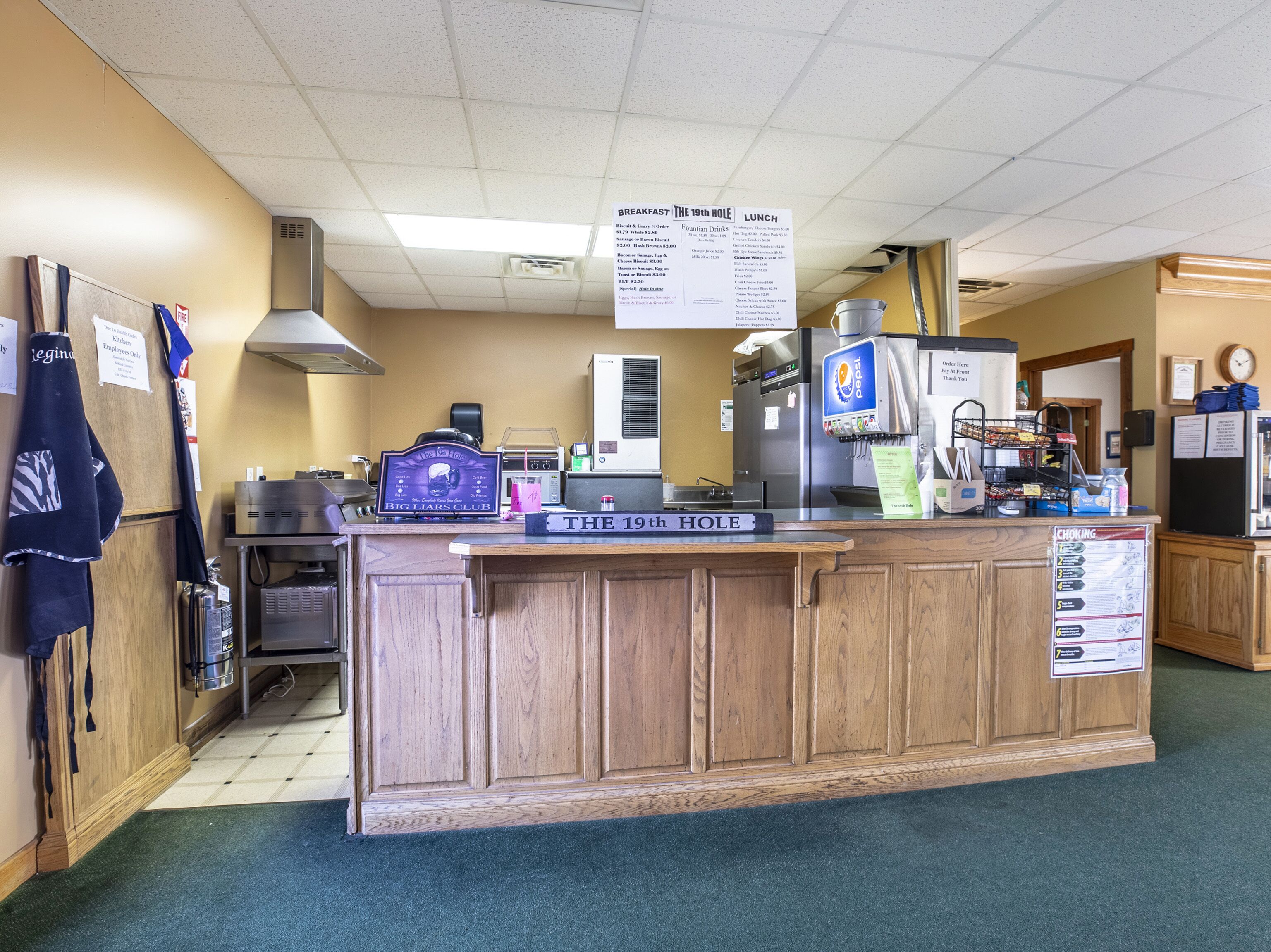 A kitchen area with a wooden counter, a coffee machine, and a menu board above the counter.