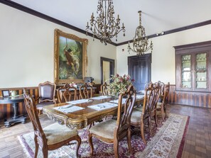 A formal dining room with a large wooden table, ornate chairs, a chandelier, and a large framed painting on the wall. - Falls of Rough Resort (Falls of Rough)